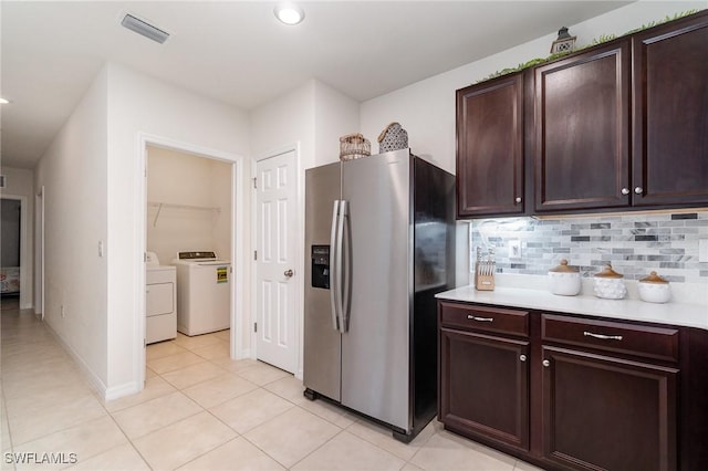 kitchen featuring stainless steel refrigerator with ice dispenser, separate washer and dryer, light countertops, backsplash, and light tile patterned floors