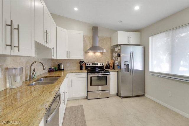 kitchen with wall chimney exhaust hood, a sink, light stone countertops, backsplash, and stainless steel appliances