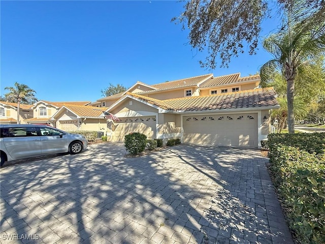 14641 Glen Cove Dr Unit 1704, Fort Myers, FL 33919 - view of front facade featuring decorative driveway, an attached garage, a tiled roof, and stucco siding
