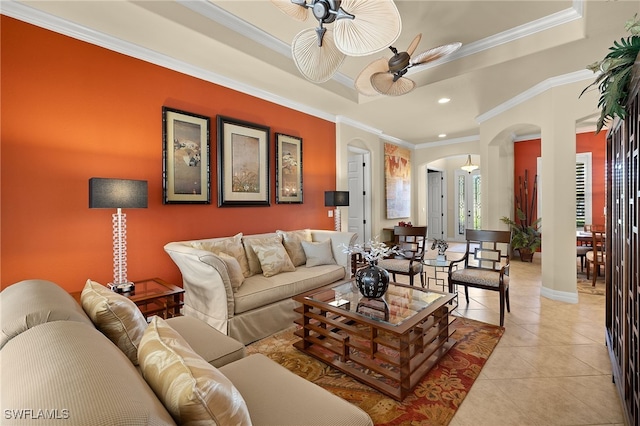 living area featuring arched walkways, light tile patterned floors, a tray ceiling, and ceiling fan