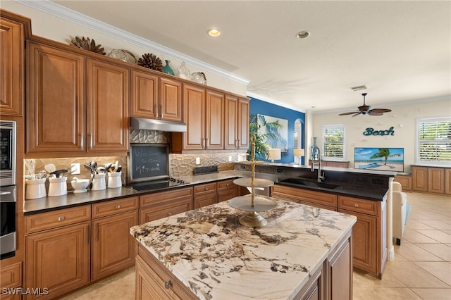 kitchen featuring black electric cooktop, a sink, a peninsula, under cabinet range hood, and crown molding