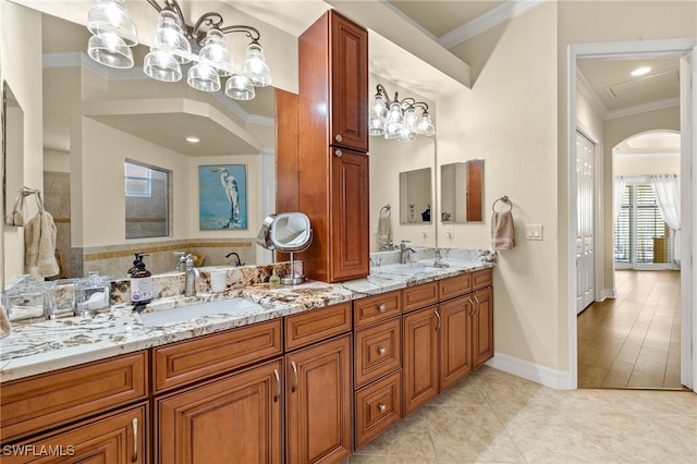 bathroom with an inviting chandelier, double vanity, tile patterned floors, crown molding, and a sink
