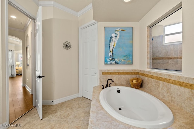 bathroom featuring a bath, crown molding, baseboards, and tile patterned floors