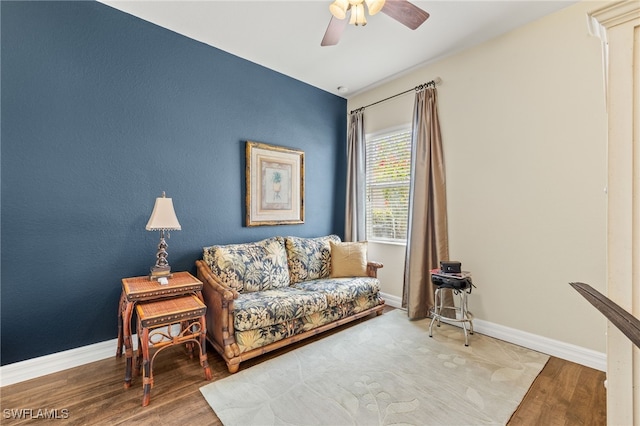 sitting room with ceiling fan, wood finished floors, and baseboards