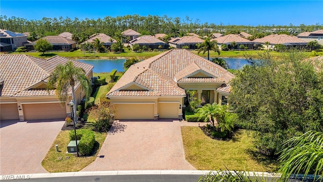 view of front of house with an attached garage, a residential view, a tile roof, and decorative driveway
