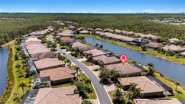 drone / aerial view featuring a wooded view, a residential view, and a water view