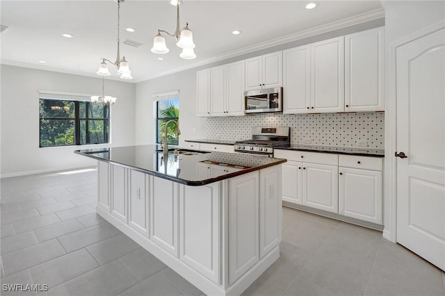 kitchen featuring dark countertops, a sink, decorative backsplash, stainless steel appliances, and a notable chandelier