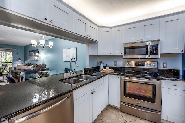 1702 Kings Lake Blvd Unit 103, Naples, FL 34112 - kitchen featuring appliances with stainless steel finishes, a sink, light tile patterned floors, and dark stone countertops