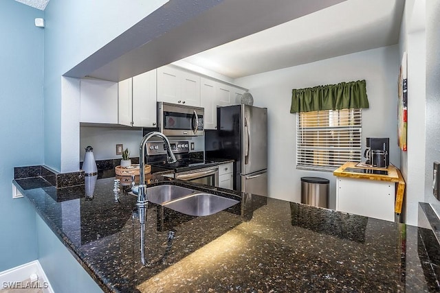 1702 Kings Lake Blvd Unit 103, Naples, FL 34112 - kitchen with appliances with stainless steel finishes, dark stone counters, a sink, white cabinetry, and a peninsula