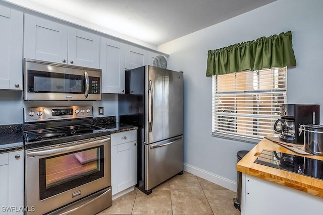 1702 Kings Lake Blvd Unit 103, Naples, FL 34112 - kitchen featuring appliances with stainless steel finishes, baseboards, wood counters, light tile patterned floors, and white cabinetry