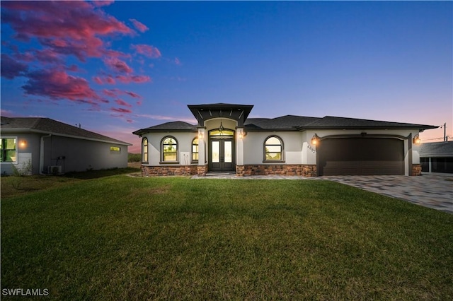 view of front of home featuring driveway, stone siding, stucco siding, french doors, and a garage