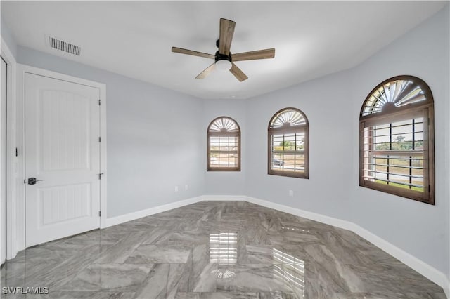 spare room with baseboards, visible vents, ceiling fan, and plenty of natural light