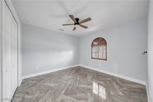 spare room with a ceiling fan, visible vents, and baseboards