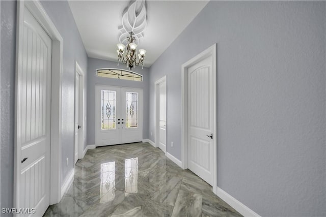 foyer entrance featuring marble finish floor, an inviting chandelier, french doors, and baseboards