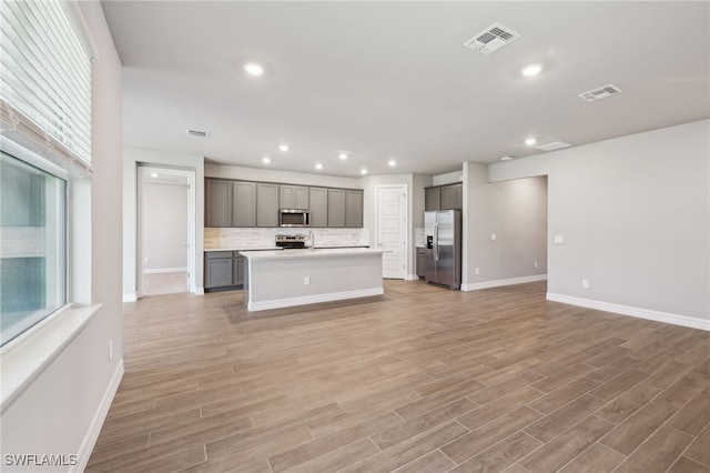 44385 Frontier Dr, Punta Gorda, FL 33982 - kitchen featuring stainless steel appliances, open floor plan, baseboards, gray cabinetry, and light wood-style flooring