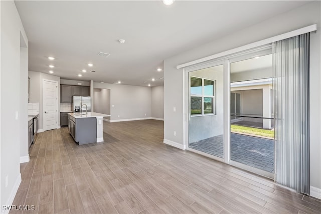 44385 Frontier Dr, Punta Gorda, FL 33982 - kitchen featuring stainless steel fridge with ice dispenser, light countertops, an island with sink, recessed lighting, and open floor plan