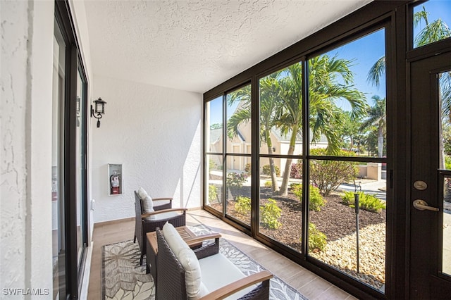 12130 Kelly Greens Blvd Unit 94, Fort Myers, FL 33908 - sunroom / solarium featuring wood finished floors, a textured ceiling, baseboards, a textured wall, and floor to ceiling windows