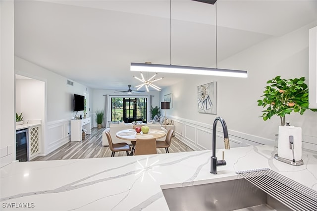 12130 Kelly Greens Blvd Unit 94, Fort Myers, FL 33908 - kitchen with a sink, a wainscoted wall, open floor plan, a decorative wall, and light stone counters
