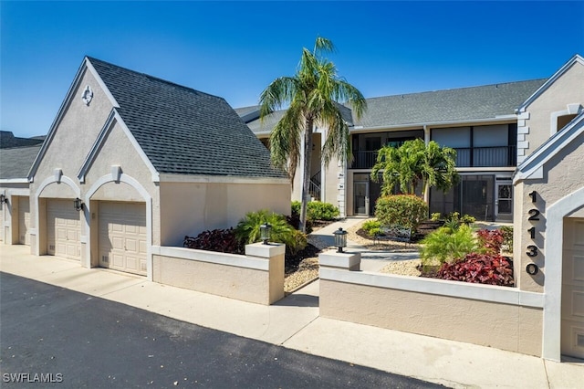 12130 Kelly Greens Blvd Unit 94, Fort Myers, FL 33908 - view of front of house with an attached garage, a shingled roof, stucco siding, and aphalt driveway