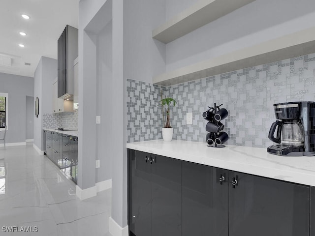 kitchen with baseboards, modern cabinets, dark cabinetry, backsplash, and light stone counters