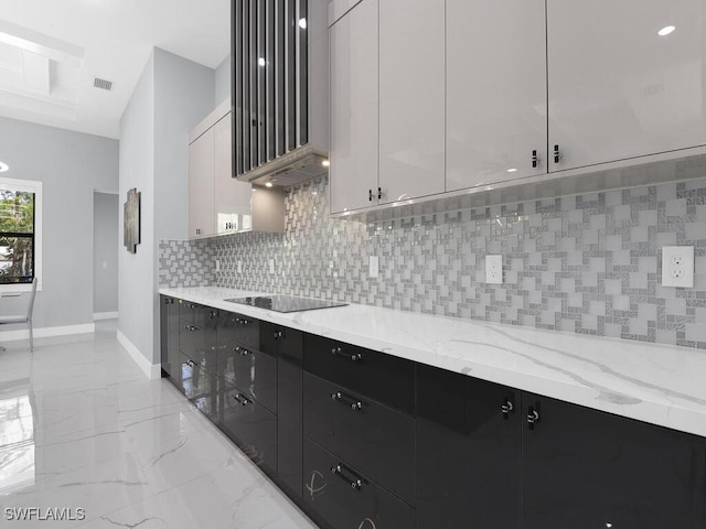 kitchen featuring baseboards, dark cabinets, black electric stovetop, decorative backsplash, and marble finish floor