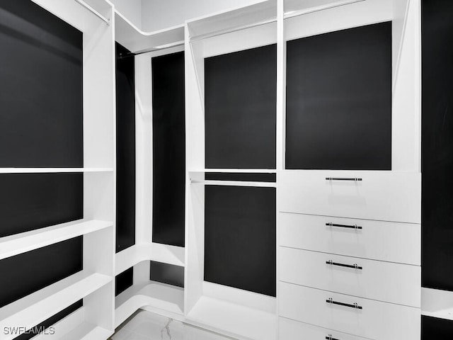walk in closet featuring marble finish floor