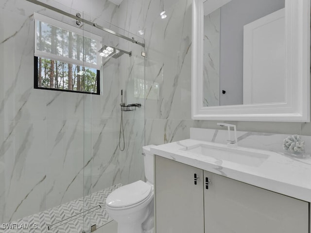 bathroom with toilet, a marble finish shower, and vanity