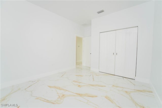 1603 E 5th St, Lehigh Acres, FL 33972 - unfurnished bedroom with marble tiled floors, baseboards, and a closet