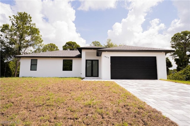 1603 E 5th St, Lehigh Acres, FL 33972 - prairie-style house with stucco siding, a garage, decorative driveway, and a front lawn