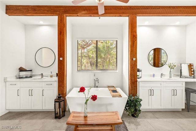 bathroom featuring two vanities, ceiling fan, a freestanding bath, and a sink