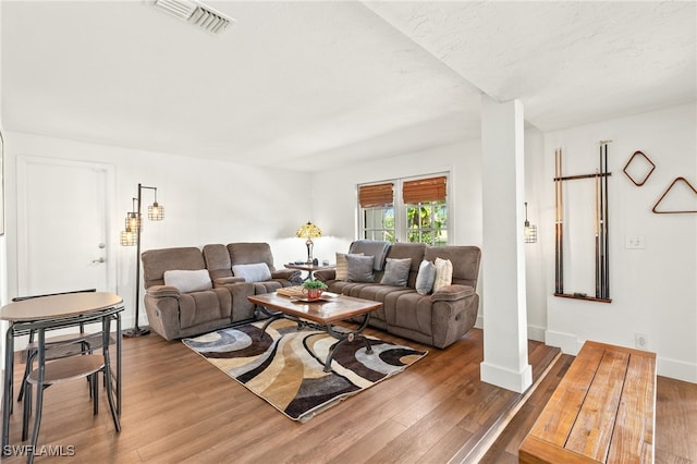 living room featuring baseboards, visible vents, and wood finished floors