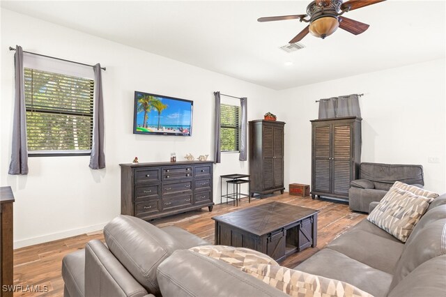 living room with baseboards, visible vents, wood finished floors, and a ceiling fan