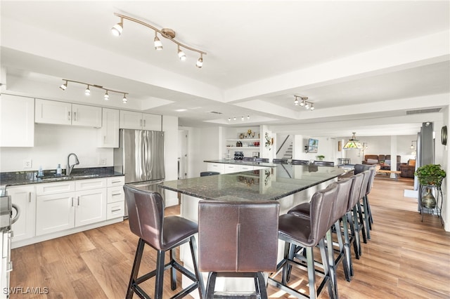 kitchen featuring a sink, freestanding refrigerator, light wood finished floors, and white cabinets