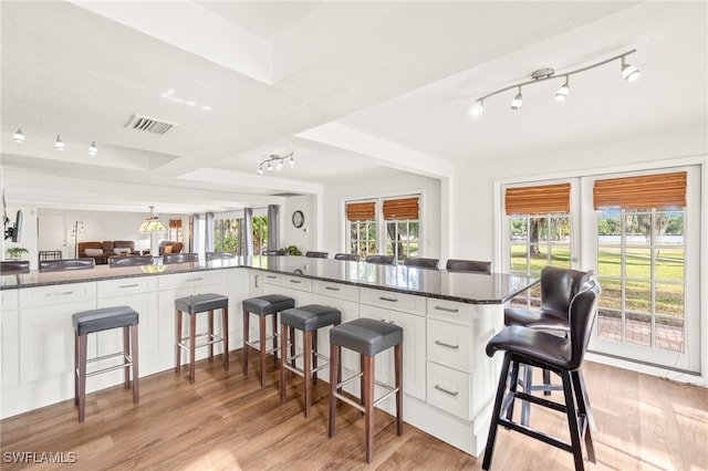 kitchen with white cabinetry, light wood finished floors, and a kitchen bar