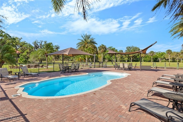 community pool featuring a patio, outdoor dining area, and fence