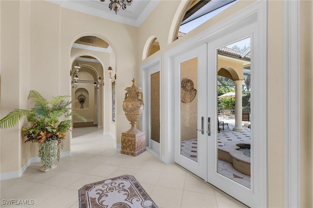 interior space with baseboards, light tile patterned floors, french doors, crown molding, and arched walkways