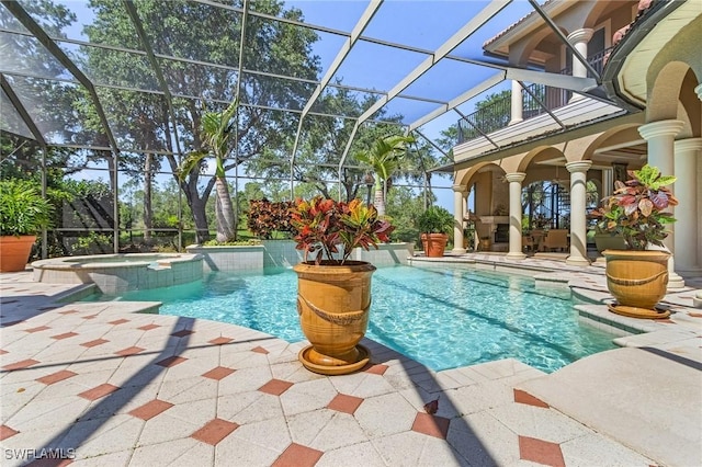 view of swimming pool featuring a pool with connected hot tub, a patio, and glass enclosure