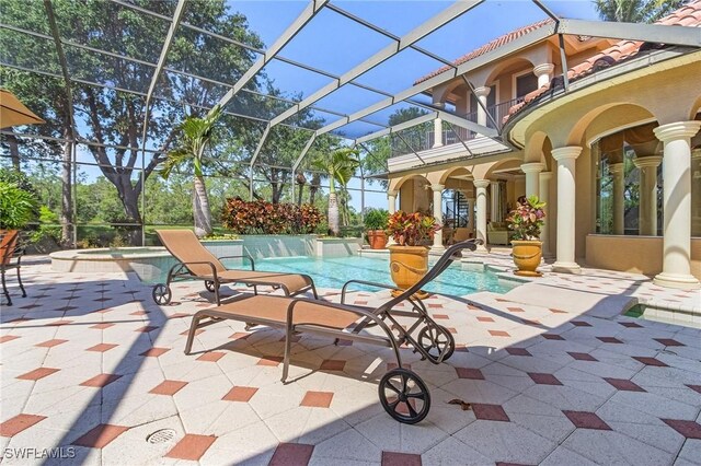 view of swimming pool featuring a lanai, a patio area, and a pool with connected hot tub