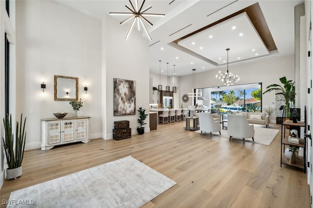 127 SW 56th Ter, Cape Coral, FL 33914 - living room featuring light wood finished floors, baseboards, recessed lighting, a notable chandelier, and a high ceiling