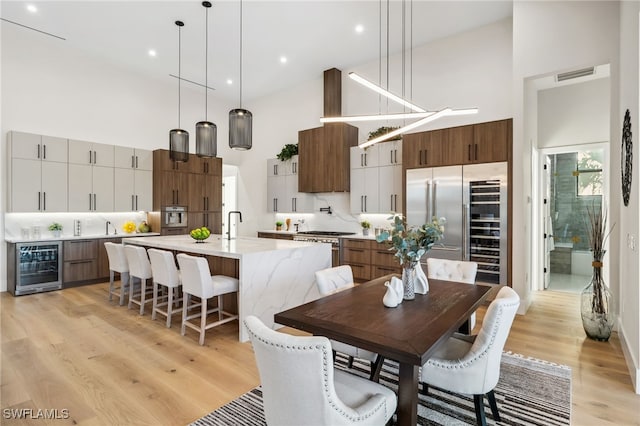 127 SW 56th Ter, Cape Coral, FL 33914 - dining room featuring visible vents, light wood finished floors, a towering ceiling, and wine cooler