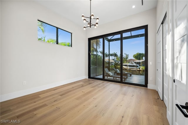 127 SW 56th Ter, Cape Coral, FL 33914 - unfurnished room featuring light wood-style flooring, an inviting chandelier, and a healthy amount of sunlight