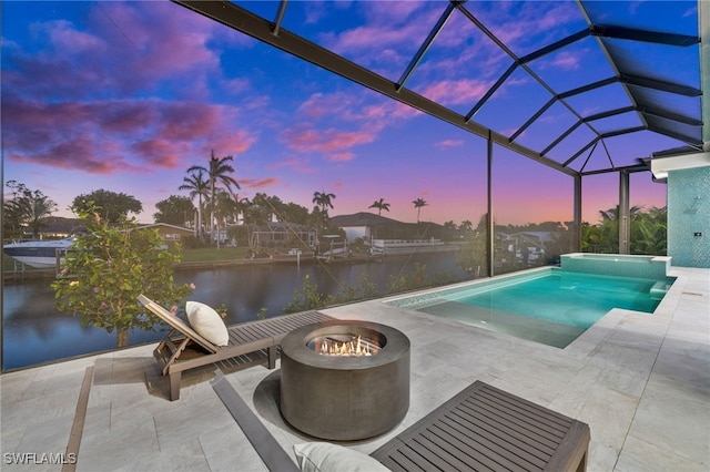 127 SW 56th Ter, Cape Coral, FL 33914 - pool at dusk with glass enclosure, a water view, a fire pit, a pool with connected hot tub, and a patio
