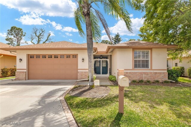 5794 Elizabeth Ann Way, Fort Myers, FL 33912 - view of front of house with stucco siding, driveway, a front lawn, brick siding, and a garage