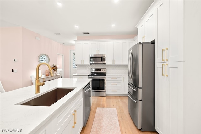 5794 Elizabeth Ann Way, Fort Myers, FL 33912 - kitchen with light wood-style flooring, a sink, white cabinets, and stainless steel appliances