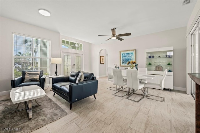 living area with arched walkways, ceiling fan, baseboards, and visible vents