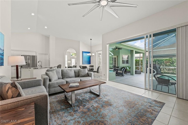 living room featuring ceiling fan with notable chandelier, high vaulted ceiling, arched walkways, recessed lighting, and light tile patterned flooring