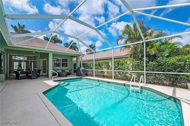 pool with area for grilling, glass enclosure, a patio, and an outdoor hangout area