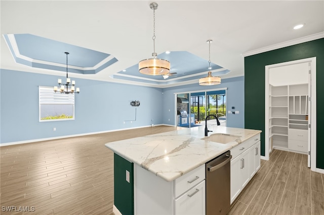 kitchen featuring stainless steel dishwasher, a tray ceiling, a sink, light wood-type flooring, and white cabinetry