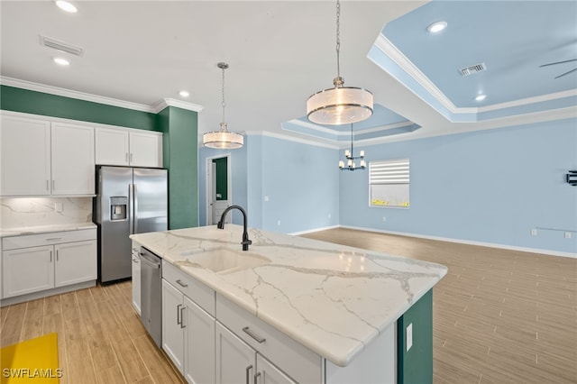kitchen featuring stainless steel appliances, a sink, visible vents, light wood-style floors, and crown molding