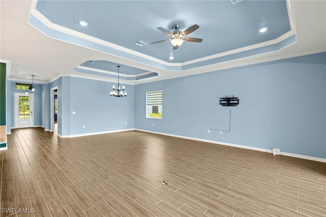 unfurnished living room featuring ornamental molding, a tray ceiling, visible vents, and ceiling fan with notable chandelier